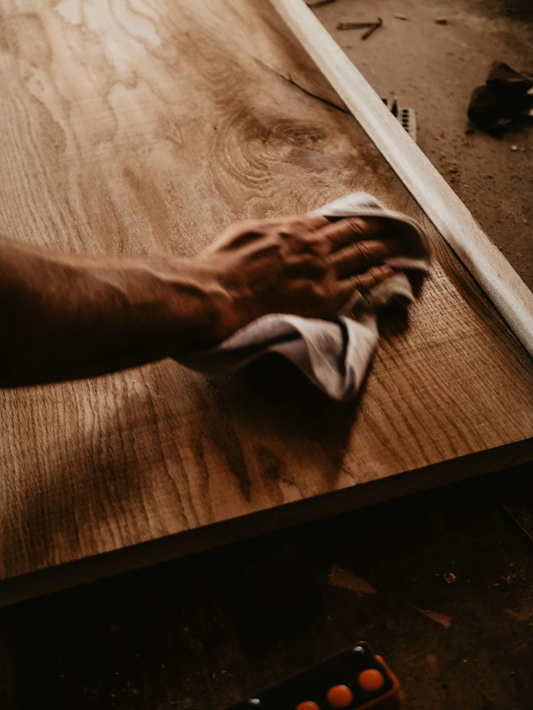 Person using spray bottle and cloth for cleaning a kitchen shelf, ensuring hygiene and cleanliness.